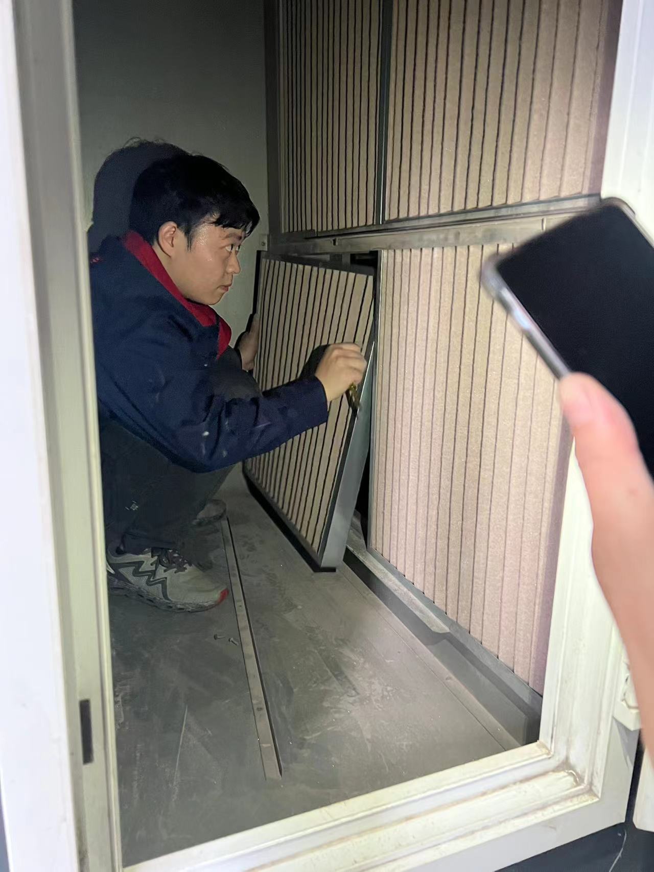 Worker replacing a filter panel in an AHU access door